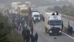 Migrants-gather-on-the-road-as-others-board-a-lorry-on-the-access.jpg